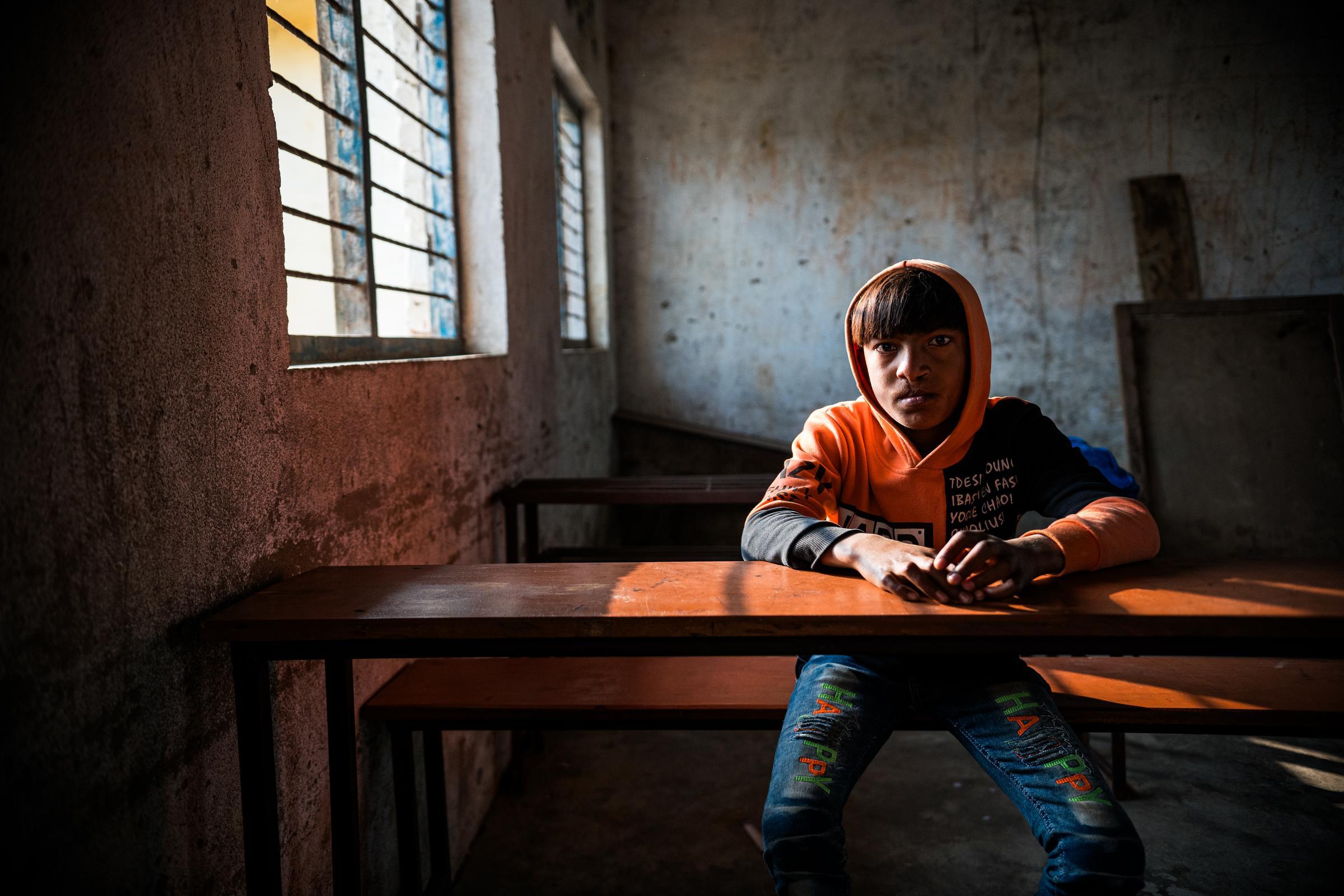 Anils größter Wunsch ist es, wieder zur Schule gehen zu dürfen. Auf dem Foto sieht man ihn, wie er in einem leeren Klassenraum an einem Tisch sitzt. (Fotos: Martin Bondzio)