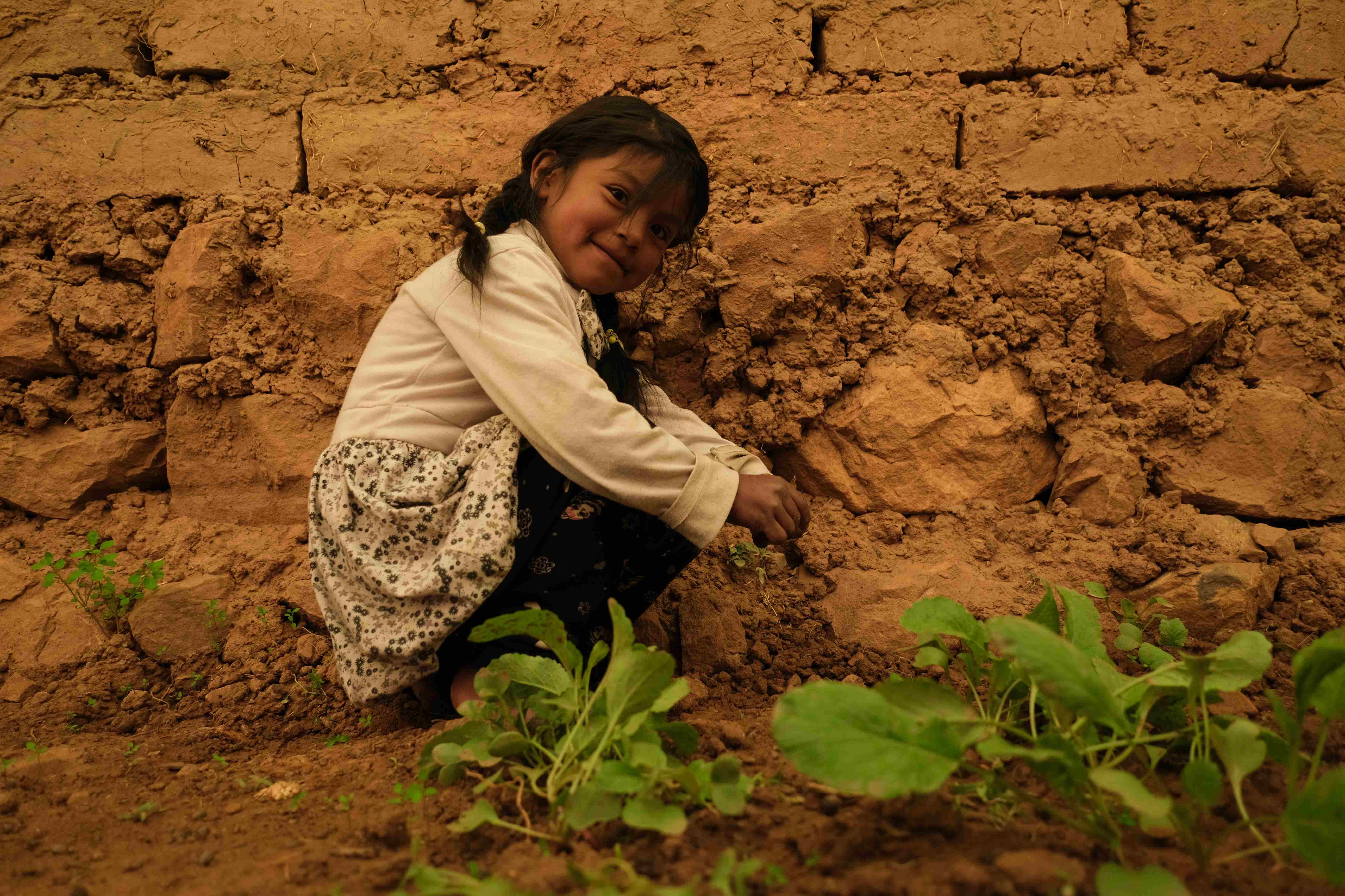 Ein kleines Mädchen sitzt vor einem Gemüsebeet. (Quelle: Mauricio Vera)